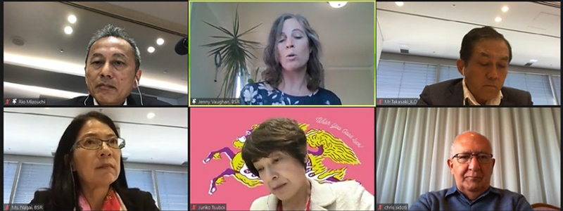 スクリーンに映し出された、リアルとオンライン参加者が参加するハイブリッドミーティングの様子